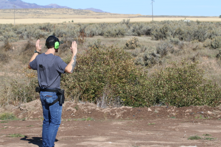 shooter with hands off and up in wilderness
