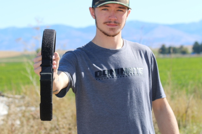 Model holding Dominate Defence Inner Belt, wearing Dominate Defense T-shirt
